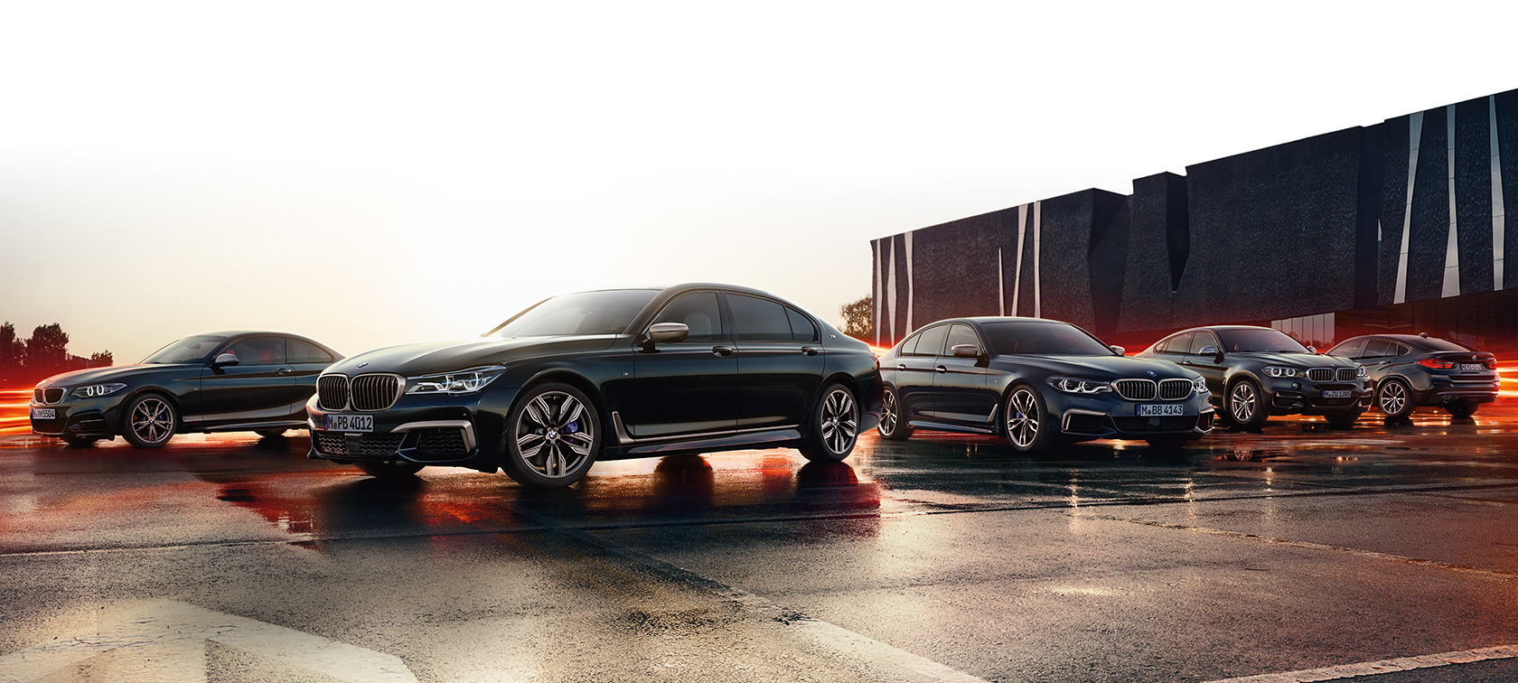 Cinco automóveis BMW da linha M Performance em um dia claro com chão molhado Cinco automóveis BMW da linha M Performance em um dia claro com chão molhado